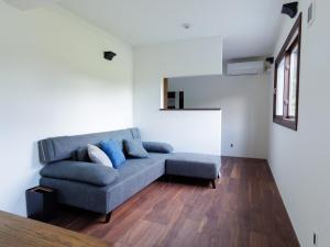 a living room with a blue couch and wooden floors at Locanda Furanora in Furano