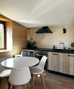 a kitchen with a white table and white chairs at La Petite Cabane in Saint-Affrique