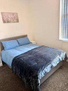 a bed in a bedroom with a blue blanket on it at Colne Hideaway in Colne