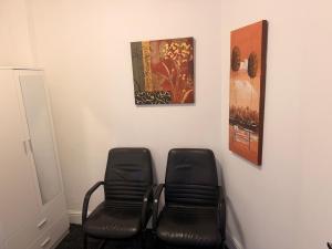 two black chairs in a waiting room with a painting at Colne Hideaway in Colne