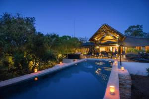 a swimming pool in front of a house at night at Vuyani Safari Lodge in Hoedspruit