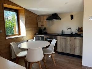 a kitchen with a table and white chairs in a room at La Petite Cabane in Saint-Affrique