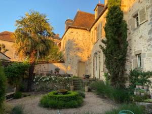 a courtyard of a house with a tree and a building at Les Chambres du 4 in Saint-Benoît-du-Sault