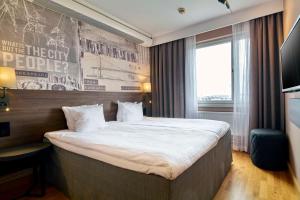 a hotel room with a large bed with white sheets at Scandic Opalen in Gothenburg