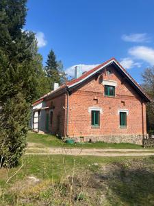 an old brick house with green windows on a field at Försterei Kalkhorst Ferienhaus am Naturschutzgebiet mit großem Garten in Neustrelitz