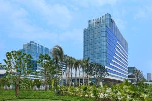 a tall glass building with palm trees in front of it at Aloft by Marriott Xiamen Xiangan in Xiamen
