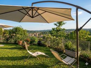 a patio with two chairs and an umbrella at ROSSO DI SERA Bed & Breakfast in Tarcento