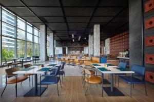 a restaurant with tables and chairs and windows at Aloft by Marriott Xiamen Xiangan in Xiamen