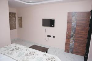 a bedroom with a bed and a tv on the wall at V Rooms in Pendurti