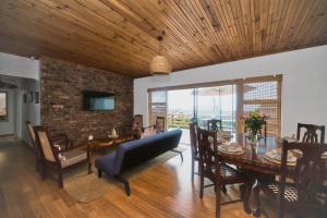 a living room with a table and chairs and a brick wall at Land's Edge Eco Friendly Cottages and Apartments in Struisbaai