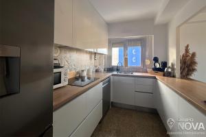 a kitchen with white cabinets and a sink and a microwave at Marina Tavernes in Tavernes de Valldigna