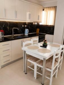 a white kitchen with a white table and chairs at Guest House Emi in Berat