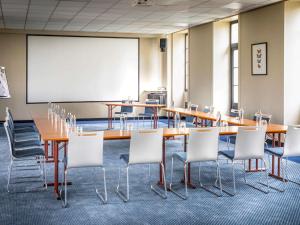 a conference room with tables and chairs and a whiteboard at Hôtel Mercure Rochefort La Corderie Royale in Rochefort