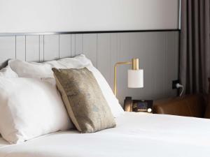 a bedroom with a white bed with a pillow and a lamp at The Sebel Brisbane Margate Beach in Redcliffe +76 photos