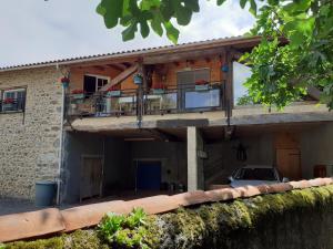 a house with a balcony and a car parked in front at La grange des chouettes in Ilheu