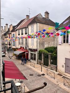 a street with buildings and colorful flags in a town at Les Appartements d Aristide Avallon in Avallon
