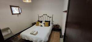 a bedroom with a bed with white sheets and yellow pillows at Casa Pura de Trevélez in Trevélez