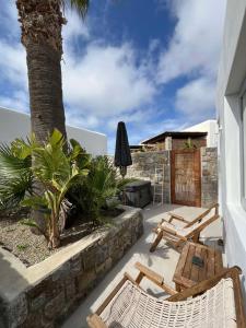 a patio with two chairs and a table and a tree at IL Vento Premium Mykonos in Mikonos