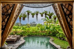 a pool in a resort with palm trees at The Queen Bamboo Ubud in Ubud