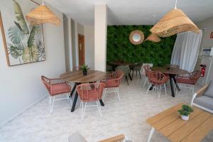 a dining room with tables and chairs and a green wall at BLUESEA Cabo de Baños in Cala en Blanes