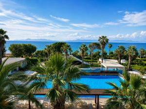 an aerial view of a resort pool with palm trees at All Senses Ocean Blue Sea Side Resort & Spa By Anayia All Inclusive Resorts in Kremasti