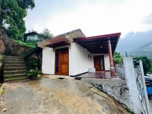 a small white house with a staircase leading to it at Mandaram Nuwara Sunset Villa in Nuwara Eliya +10 photos