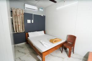 a small room with a bed and a chair at Devi Palace Pattabiram in Tandurai +21 photos