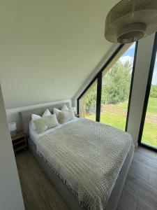 a bedroom with a bed and a large window at Winnica Osada Moszczonne in Moszczonne