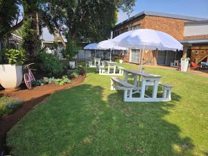 a picnic table and umbrellas in a yard at Zhantique Guest House 2- Unit 1 in Boksburg