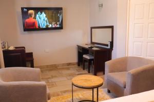 a living room with a tv and a chair and a table at Villa de Chazha Guesthouse in Francistown