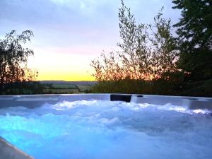 a tub filled with snow with a sunset in the background at Les Logis de Léa in Saint-Beauzély