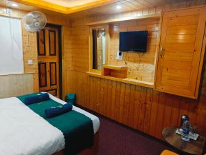 a bedroom with a bed and a flat screen tv at K2 Alpine Hotel in Pahalgām