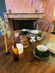 a wooden table with plates of food and a fireplace at Les Chambres du 4 in Saint-Benoît-du-Sault
