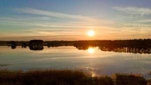 a sunset over a lake with the sun reflecting on the water at Uroczy zakątek in Silice