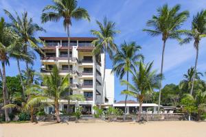 a hotel on the beach with palm trees at Rayong Chalet Hotel And Resort in Klaeng