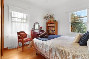 a bedroom with a bed and a chair and a window at Retro Retreat in Highton