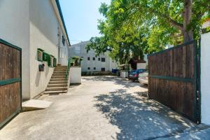 a driveway with a fence and a tree and a house at Apartmani Juricev Vodice in Vodice