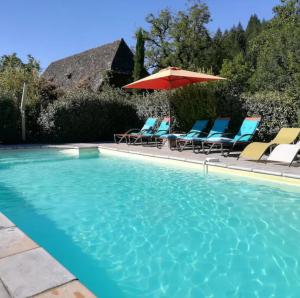 a swimming pool with chairs and an umbrella at La Vie en Le Reve kamers, chambre d'hôtes in Cassaniouze