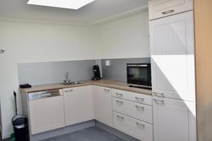 a kitchen with white cabinets and a microwave at Eb & Vloed in Petten