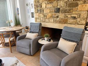 a living room with two chairs and a stone fireplace at Myrtos Olive Seaside Villa in Myrtos