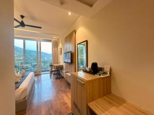a room with a bed and a desk with a television at ARNISA Kasauli - A Boutique Hotel in Kasauli