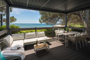 a deck with a couch and a table and the ocean at Boutique Camping Materada Beach in Poreč
