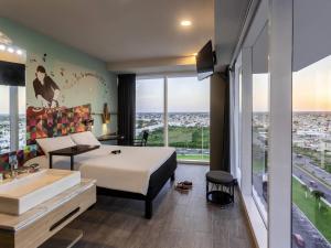 a bedroom with a bed and a sink and a large window at Ibis Styles Merida Galerias in Mérida +111 photos