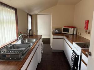 a kitchen with a sink and a microwave at Preston Villa, spacious ground floor apartment in Buckie