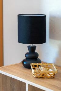 a black lamp sitting on a table with a basket at AppartHotel le Nid Marin in Aytré