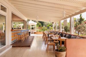 a restaurant with tables and chairs on a patio at Dominoes Corfu in Ipsos