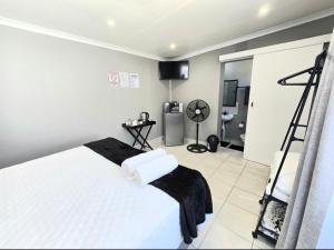 a bedroom with a white bed with a black blanket at Zhantique Guest House 2- Unit 1 in Boksburg