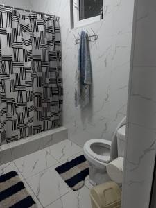 a bathroom with a toilet and a shower curtain at Friendly House in Bokonbayevo