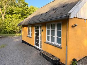 a small yellow building with a large window at Krummeled Rooms & Shelter by the forest in Hasle