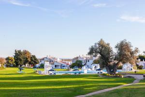 a green park with a swimming pool and houses at Pedras del Rei in Tavira